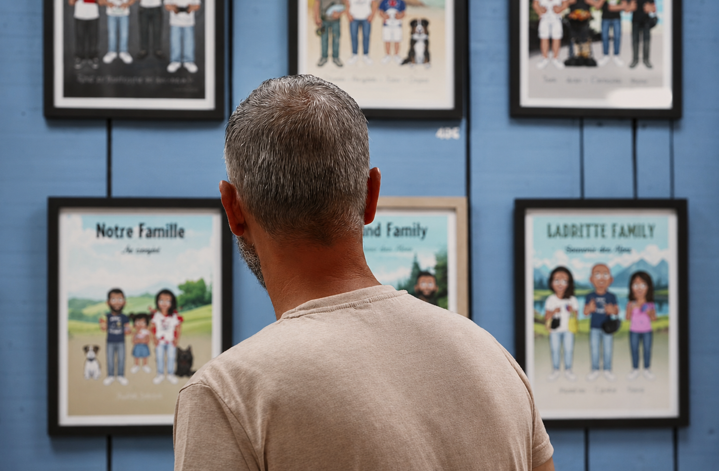 Un visiteur devant le mur de portraits de famille encadrés